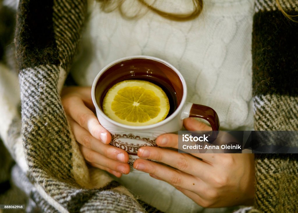 Cup of tea Cup of tea with an orange slice in the hands of a girl wrapped in plaid Horizontal Stock Photo