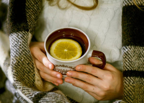 Cup of tea Cup of tea with an orange slice in the hands of a girl wrapped in plaid кружка stock pictures, royalty-free photos & images