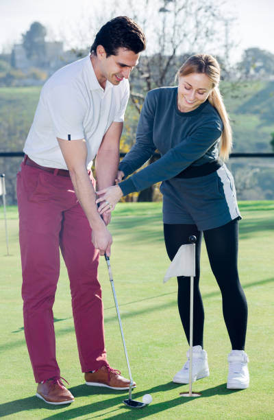 istock Woman teaches man to play golf 888063526
