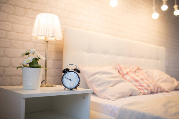 An alarm clock near the bed stock photo