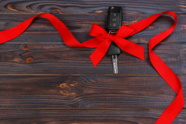 istock Car key with colorful bow on wooden background 888074824