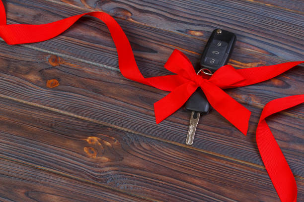 istock Car key with colorful bow on wooden background 888074862
