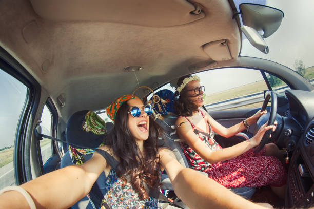 Women having fun in a road trip Two cheerful hipster women traveling in car i a sunny day bizarre fashion stock pictures, royalty-free photos & images