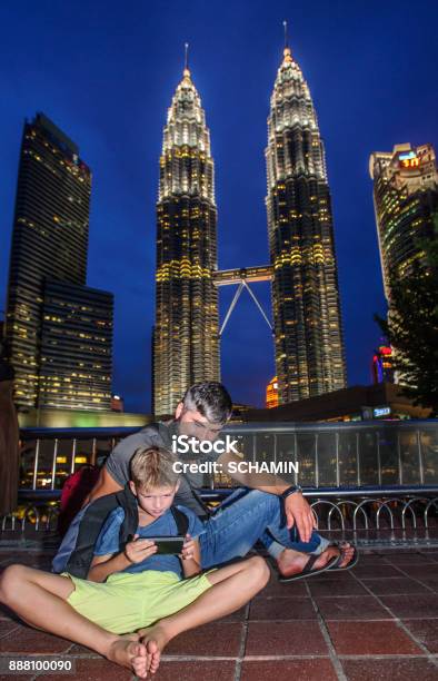 Backpackers In A Big City Father And Son Happy And Excited Together Watching Video On Phone During The Malaysia Trip Holiday Vacation Traveling Abroad Concept Copy Space Kuala Lumpurs Landmark Stock Photo - Download Image Now