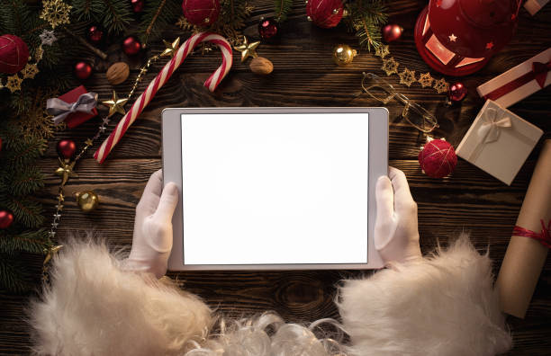 Santa Claus hands holding blank digital tablet Close up of Santa Claus hands holding blank digital tablet with copy space scrolling photos stock pictures, royalty-free photos & images