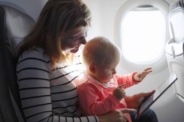 istock Mom and child playing tablet while flying on plane. 888113614