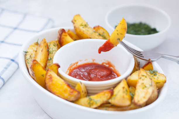 istock Baked potato slices with herbs in a white dish 888124058