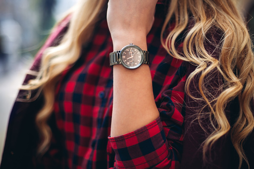 Elegant outfit. Closeup of wrist watch on the hand of stylish woman. Fashionable girl on the street. Female fashion.