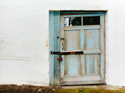 Closed wooden door in old concrete white wall