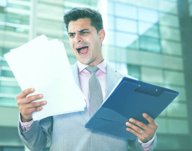 istock Dissatisfied businessman holding papers 888140448