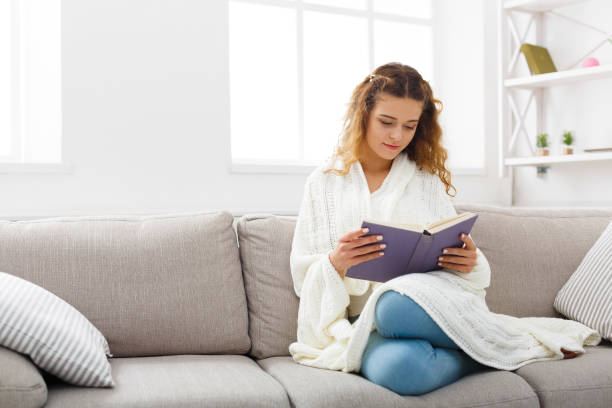istock Cozy home. Young thoughtful woman with book 888150098