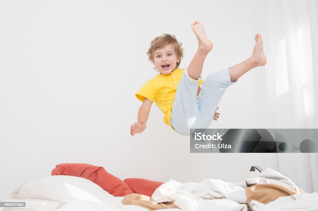 Cheerful little boy  jumping on bed at home Child Stock Photo