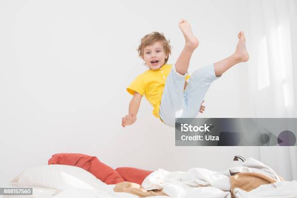 Cheerful Little Boy Jumping On Bed At Home Stock Photo - Download Image Now - Child, Vitality, Jumping