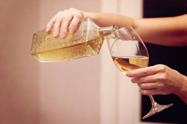 A woman pours wine into a wine glass.