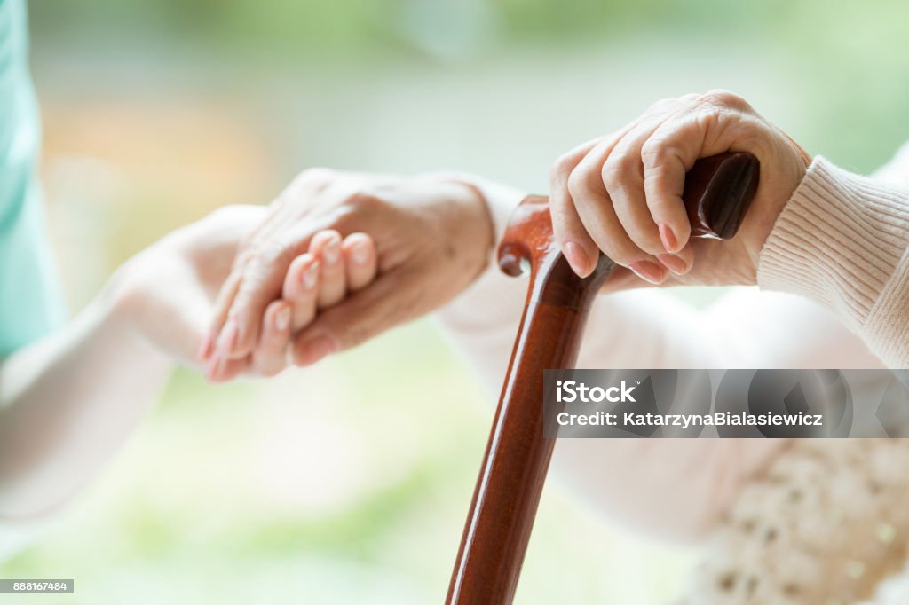 Elder person supported on stick Elder person supported on wooden stick during rehabilitation in friendly hospital Home Caregiver Stock Photo