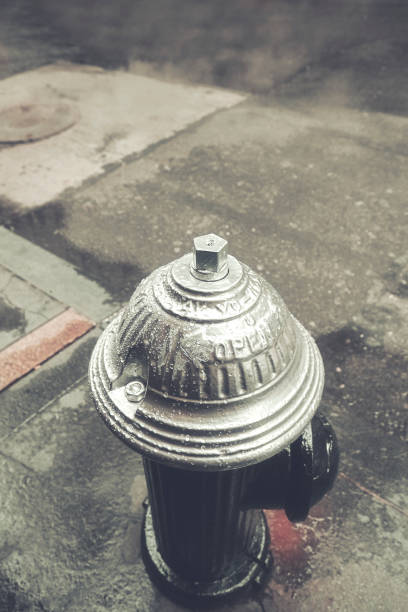 A black and white image of a fire hydrant and gravel in front of a block wall.