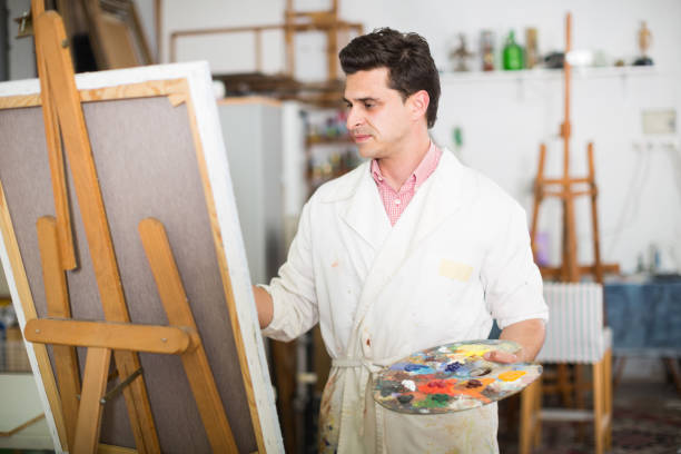istock Man near easel painting on canvas 888182752