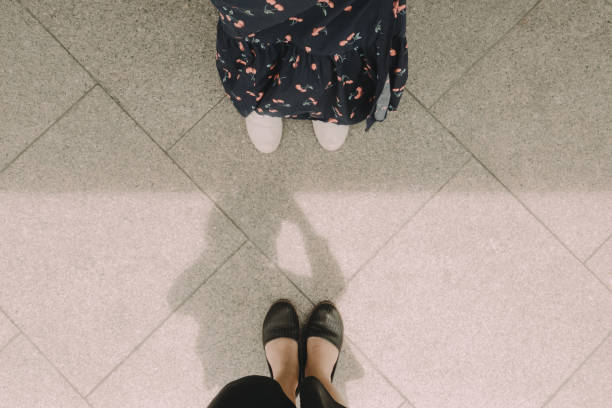 selfie of two feet with girl and her friend on floor pattern,flat lay of simple background with light and shadow