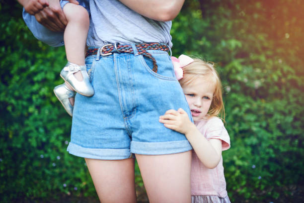 Having trouble letting go Shot of a little girl holding onto her mother during a day outdoors shy stock pictures, royalty-free photos & images