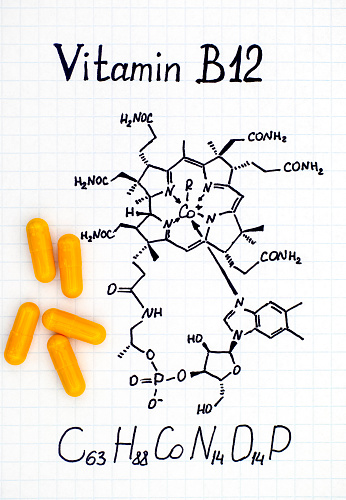Chemical formula of Vitamin B12 and yellow pills. Close-up.