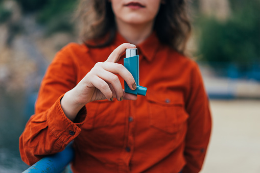 Mujer joven con un inhalador de asma al aire libre photo