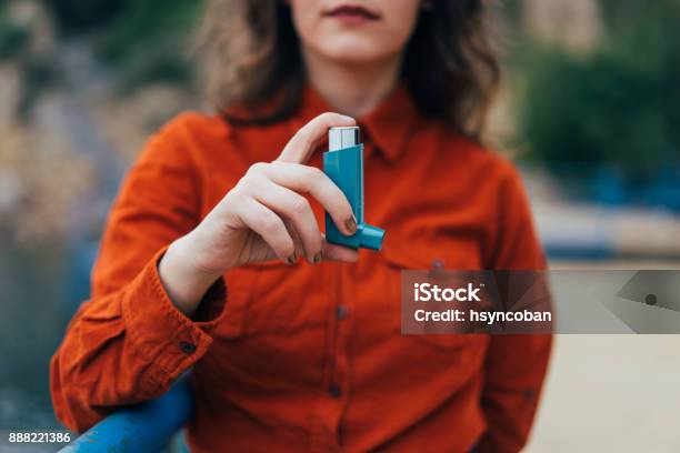 Young Woman Using An Asthma Inhaler Outdoors Stock Photo - Download Image Now - Asthmatic, Asthma Inhaler, Spray