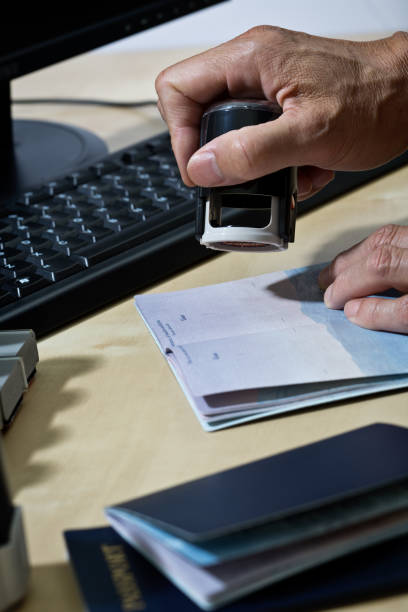 us border security, homeland security, pass prüfstation für einwanderung - customs official examining emigration and immigration document stock-fotos und bilder