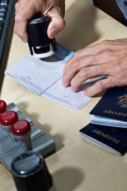 us border security, homeland security, pass prüfstation für einwanderung - customs official examining emigration and immigration document stock-fotos und bilder