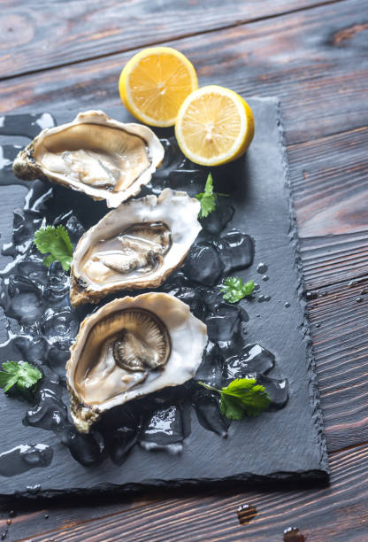 ostras cruas sobre a placa de pedra preta - prepared oysters prepared shellfish shucked seafood - fotografias e filmes do acervo