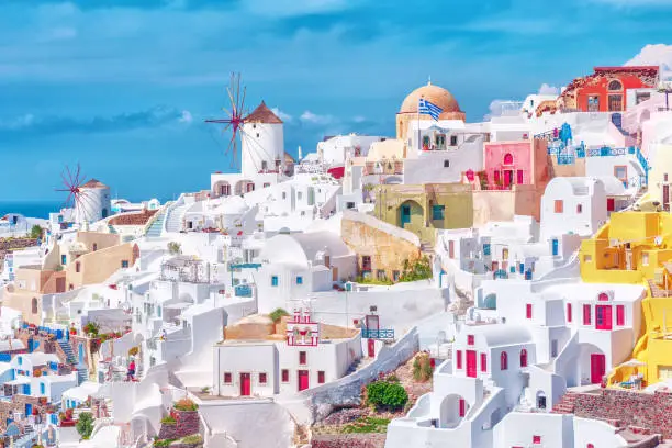Photo of Stunning, amazing and beautiful classic white and caramel  color Greek architecture with unbelievable wind mills on Santorini volcano Cyclades Caldera island in warm waters of Aegean sea in Greece.