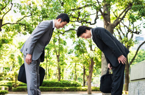 curvando - dois empresários japoneses cumprimentando uns aos outros em tóquio - humility - fotografias e filmes do acervo