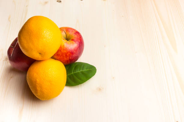 Apple and orange on a wooden board