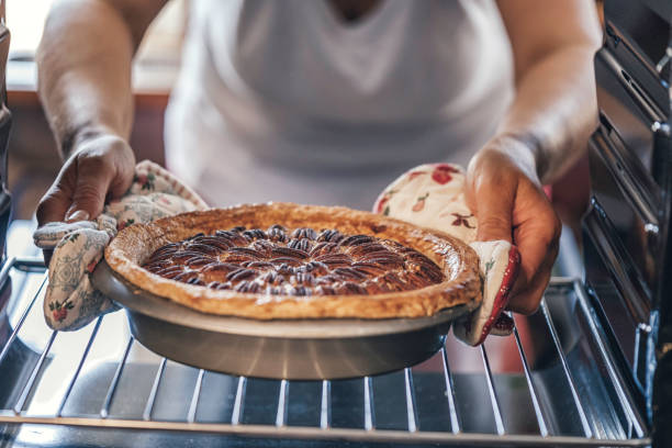 выпечка пекан пирог в духовке для праздников - cooking thanksgiving women baking стоковые фото и из�ображения