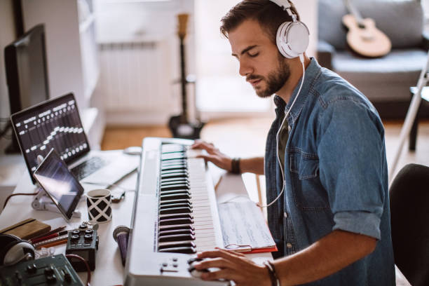 Focused Young Artist Playing Electric Piano Inspired Young Artist Playing Electric Piano In His Comfortable Home keyboard instrument stock pictures, royalty-free photos & images