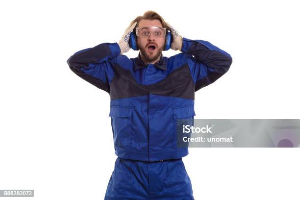 Surprised Worker In Safety Glasses Is Standing With His Mouth Holding His Headphones Stock Photo - Download Image Now
