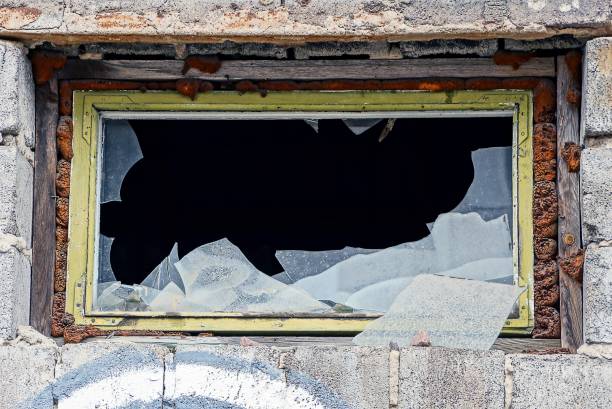 istock a small window with broken pieces of glass on a brick building 888306938