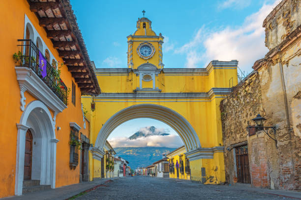 Yellow Arch of Antigua The famous architecture and yellow arch in the main street of Antigua at sunrise with the active Agua volcano in the background, Guatemala. guatemala stock pictures, royalty-free photos & images