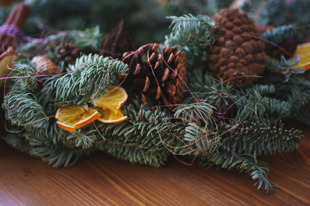 istock Christmas wreath of spruce branches handmade adorned with cones, dried fruit and oranges for the New Year mood. 888418498