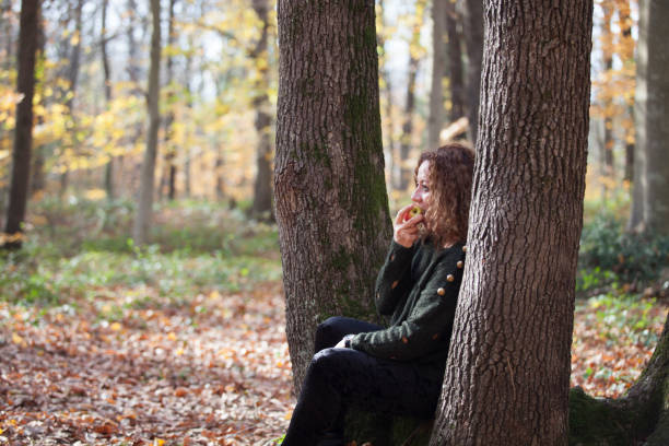 istock woman eating an apple in the woods 888420992