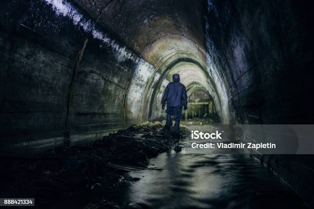 Sewer Tunnel Worker In Chemical Protective Suite In Underground Gassy Sewer Tunnel Stock Photo - Download Image Now