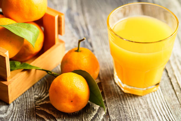 istock Glass of fresh juice and mandarins on table 888421874