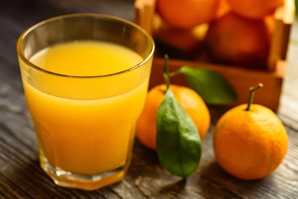 istock Glass of fresh juice and mandarins on table 888422268