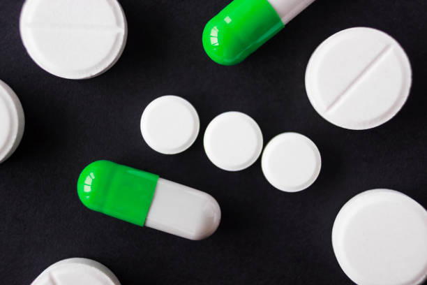 istock tablet and pill of different sizes on black background, macro 888437984