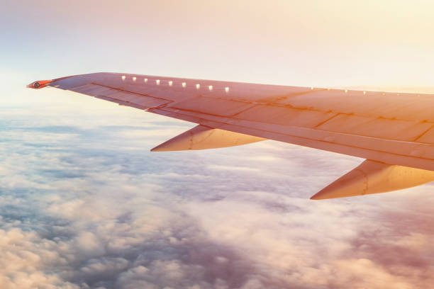 istock Airplane wing in sky with clouds and sun shine. 888465750