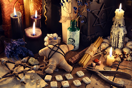 Voodoo doll, black candles, pentagram and old books on witch table