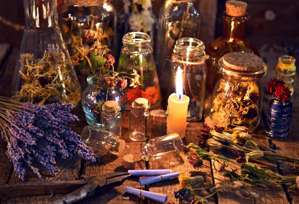 Bottles with herbs, lavender flowers, paper scrolls and magic objects stock photo
