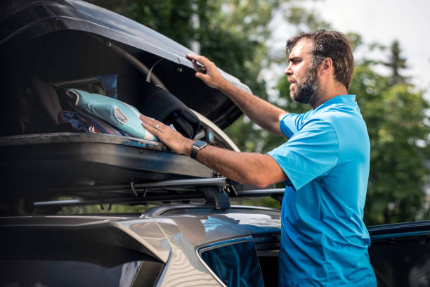 istock Men Filling Cargo Box Container on Roof Rack for Vacations 888512024