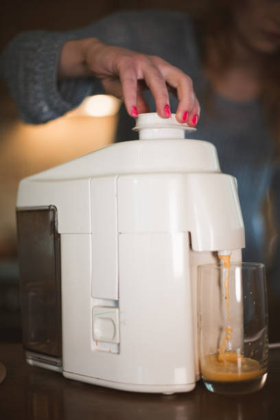 istock Close-up of making fruit juice with an electric juicer 888540854