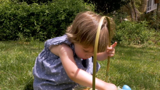 Beautiful little innocent girl looking through her Easter basket in slow motion