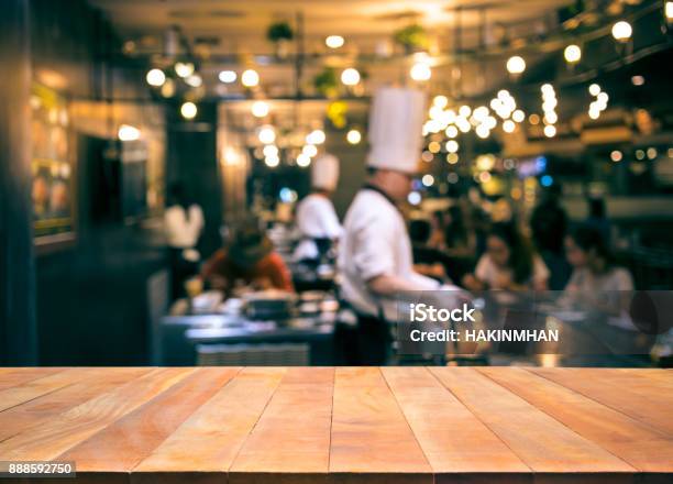 Wood Table Top With Blur Chef Cooking In Bar Restaurant Stock Photo - Download Image Now